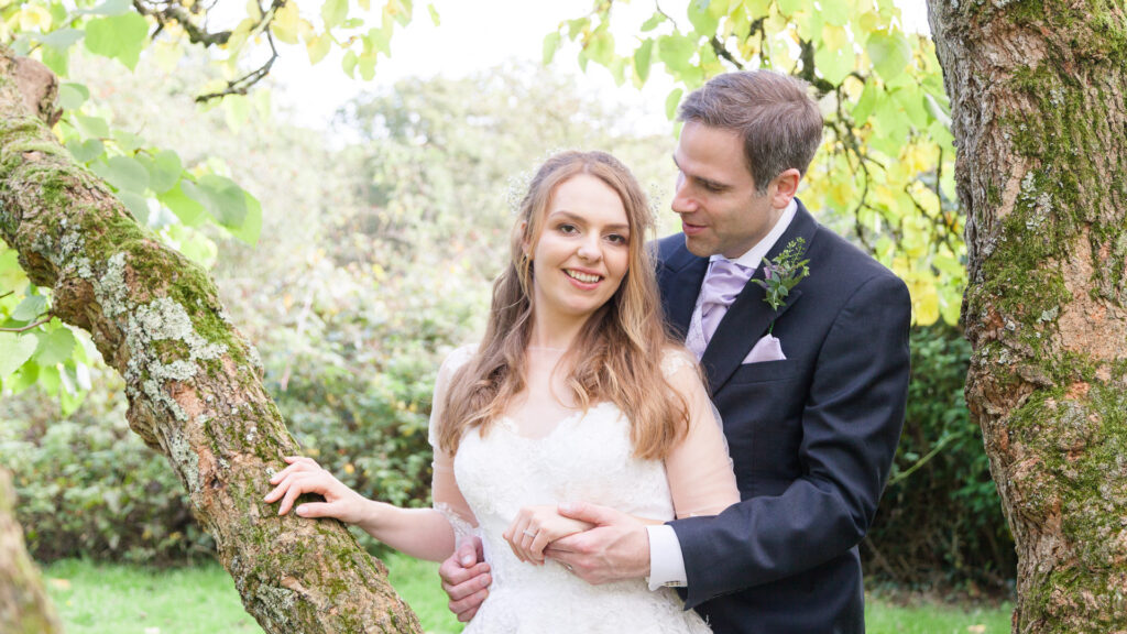 Bride and groom pose for wedding portrait beneath tree