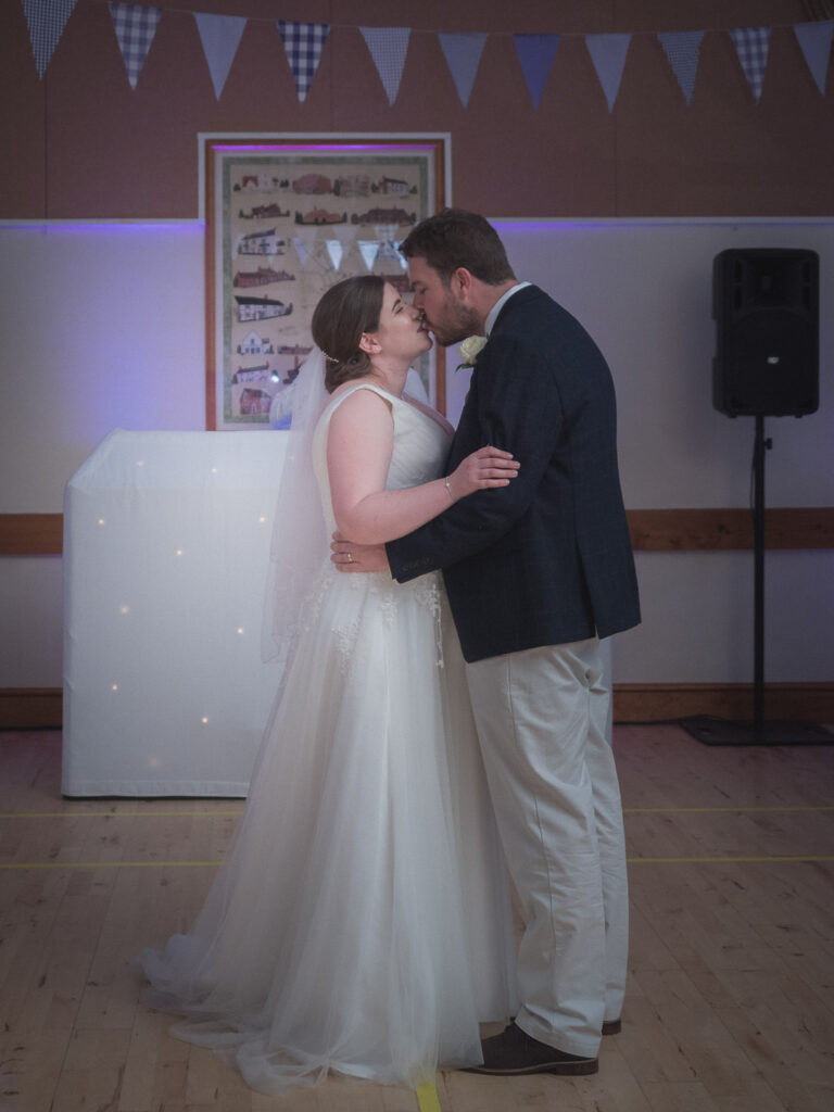 Bride and groom kiss during first dance at wedding reception