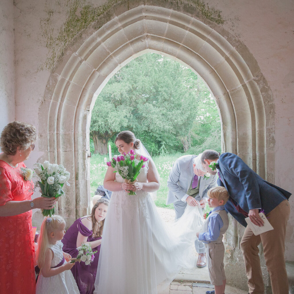 Bride and bridal party in English country church porch just before wedding service