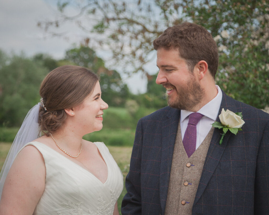 Bride and groom smile at each other after classic English country church wedding