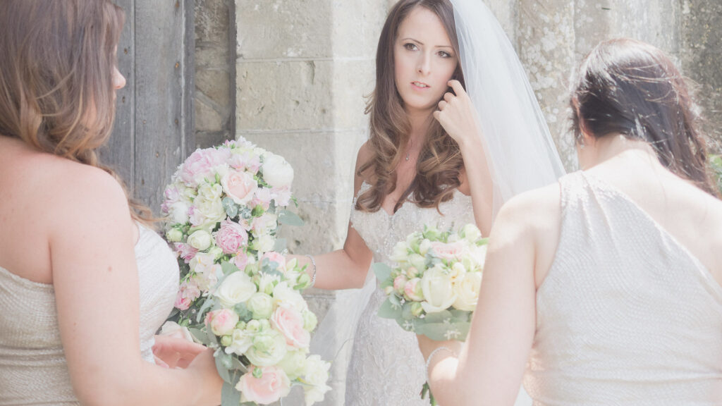 Bride and bridesmaids holding bouquets outside ancient church