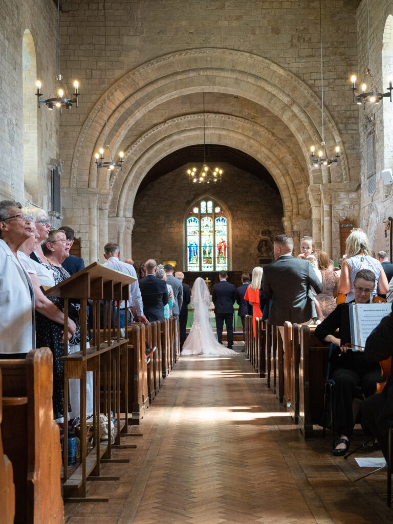 Wedding couple at altar in Portchester Church seen from rear of nave