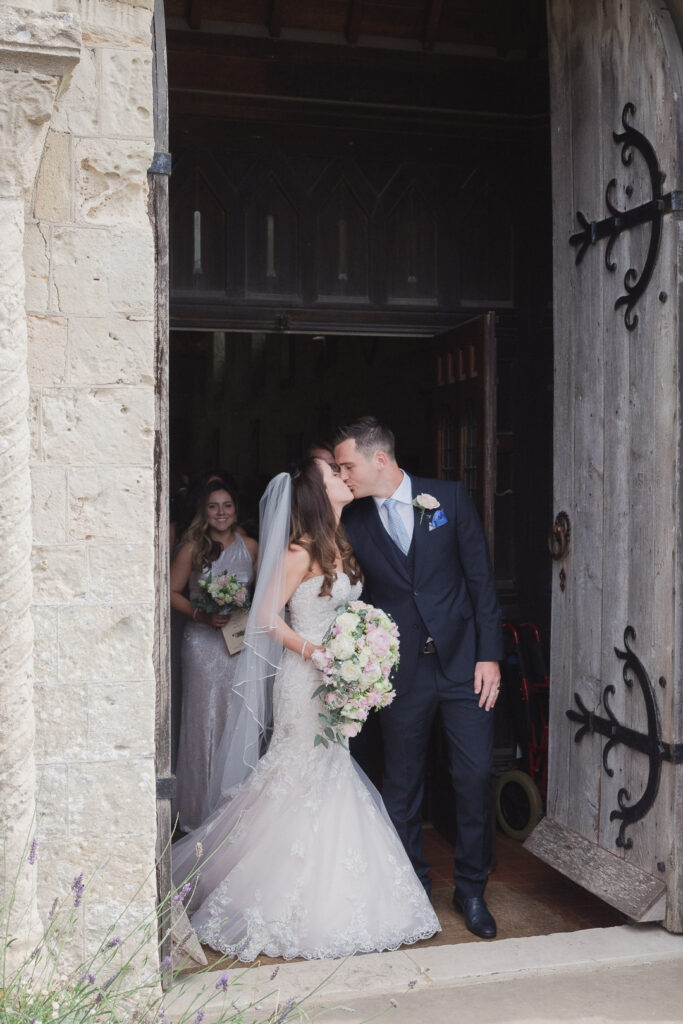 Bride and groom kiss as they leave ancient church