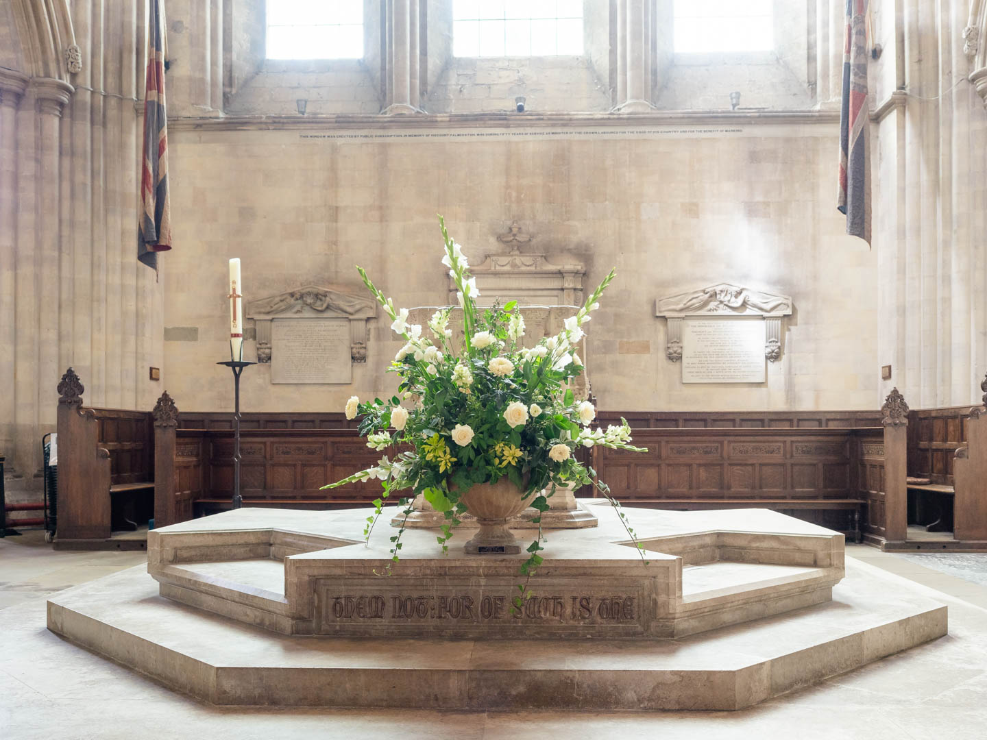 An extravagant display of white roses and lilies  in front of the font at Romsey Abbey