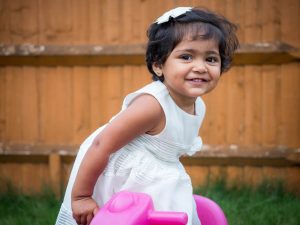 Indian girl toddler wearing a white dress in a back garden