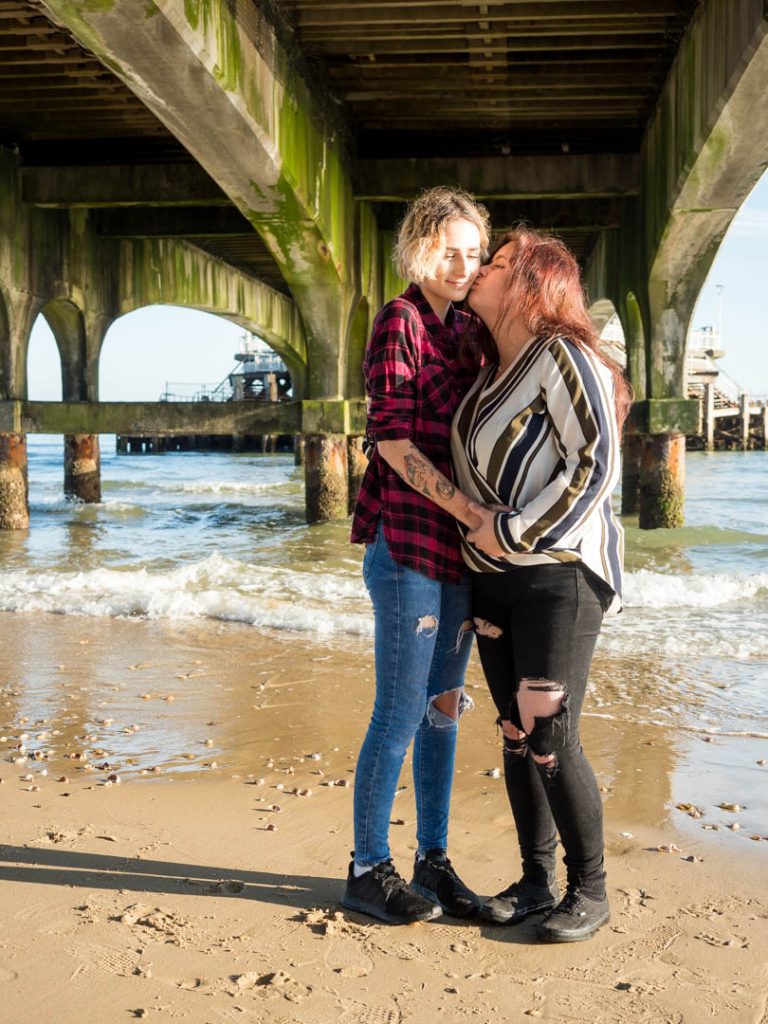 Lesbian girl kisses her partner beneath Bournemouth Pier