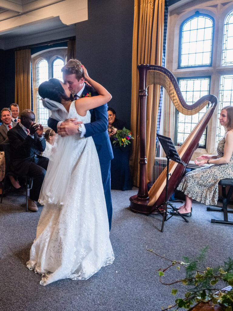 Bride and groom kiss passionately as guests applaud during their wedding ceremony
