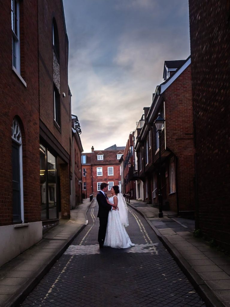 Dramtic portrait of bride and groom in city side street at sunset