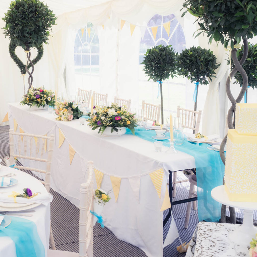 Vintage-styled top table and ornamental topiary in The Orangery Suite marquee