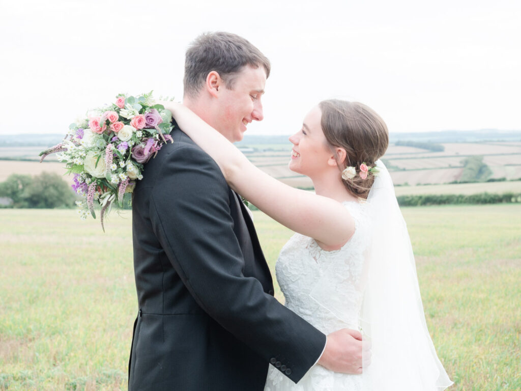Michaela and Rupert embrace with her bridal bouquet behind his neck