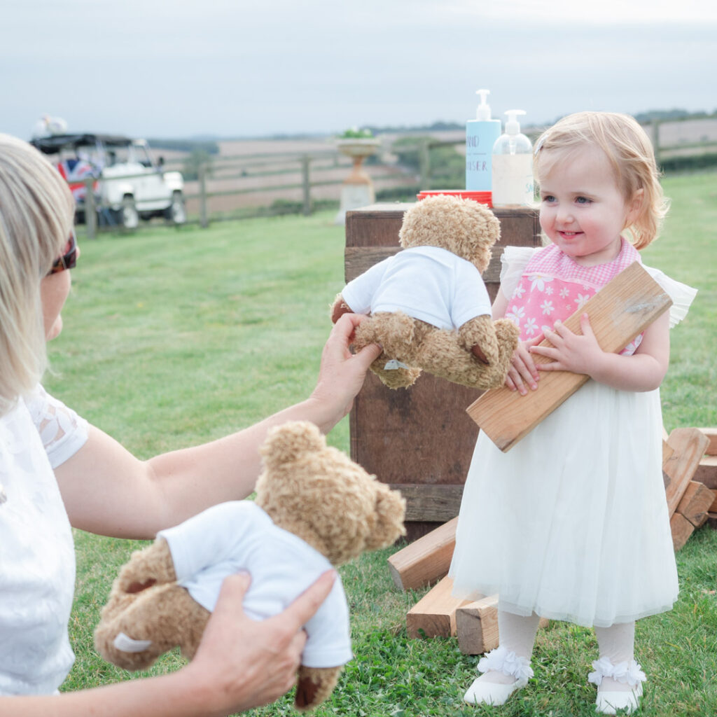 Woman offer smiling little girl a teddy bear