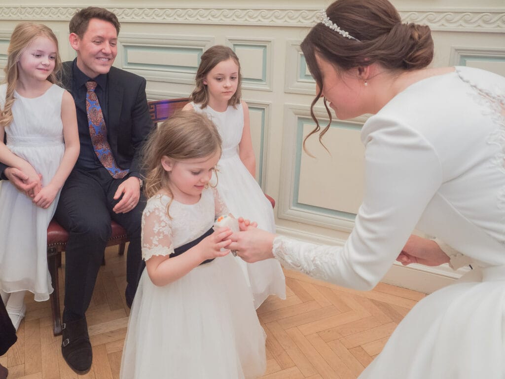 Bride gives flower girl an iced cup cake
