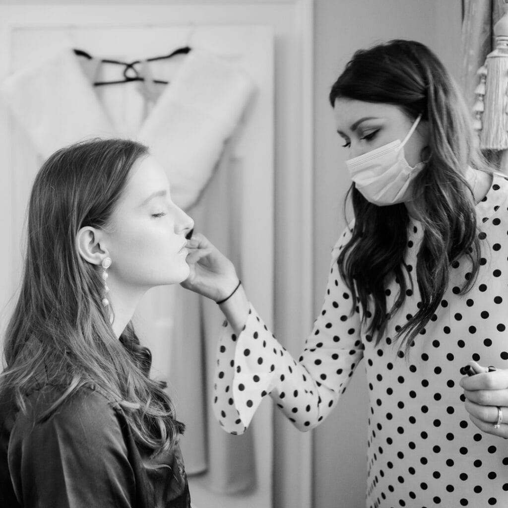 Make-up artist powders a bridesmaid's cheek