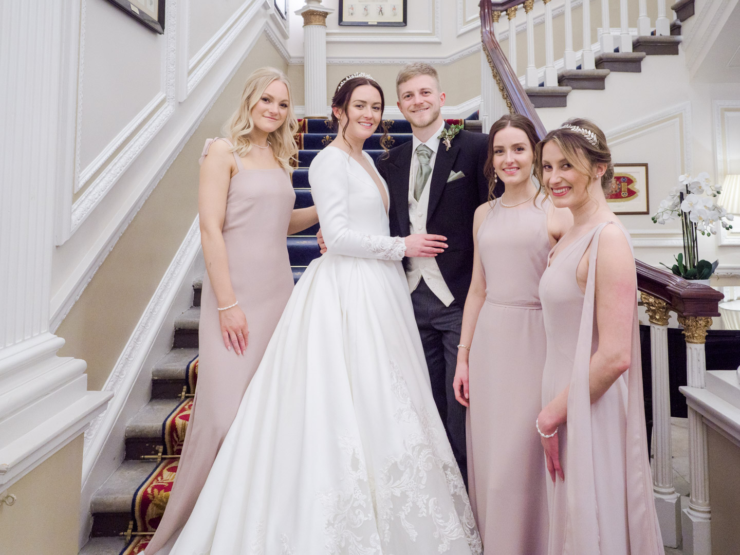 Bride, groom and bridesmaids on the stairs at the Naval and Military Club