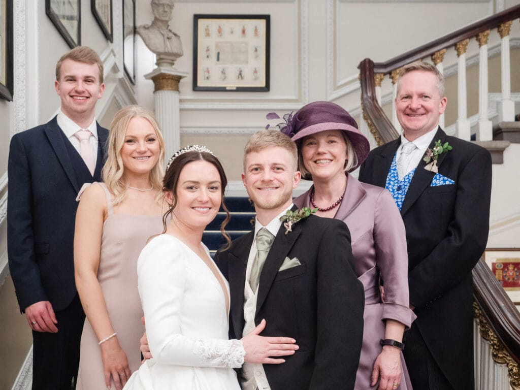 Bride and groom with family on the stairs at the Naval and Military Club