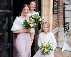 Bridesmaids and a flower girl smile with their bouquets for the camera