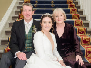 Bride seated with parents on the stairs at the Naval and Military Club
