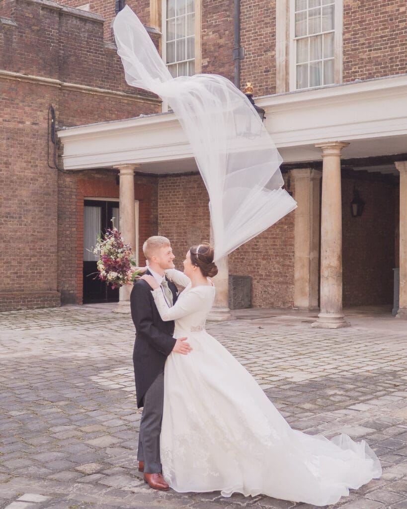 Bride holds her groom while her veil is  blown vertical by Storm Eunice