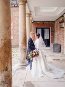 Bride and groom kiss beneath a covered walkway