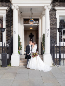 Bride and groom framed by the In and Out portico pillars at the Naval and Military Club, London