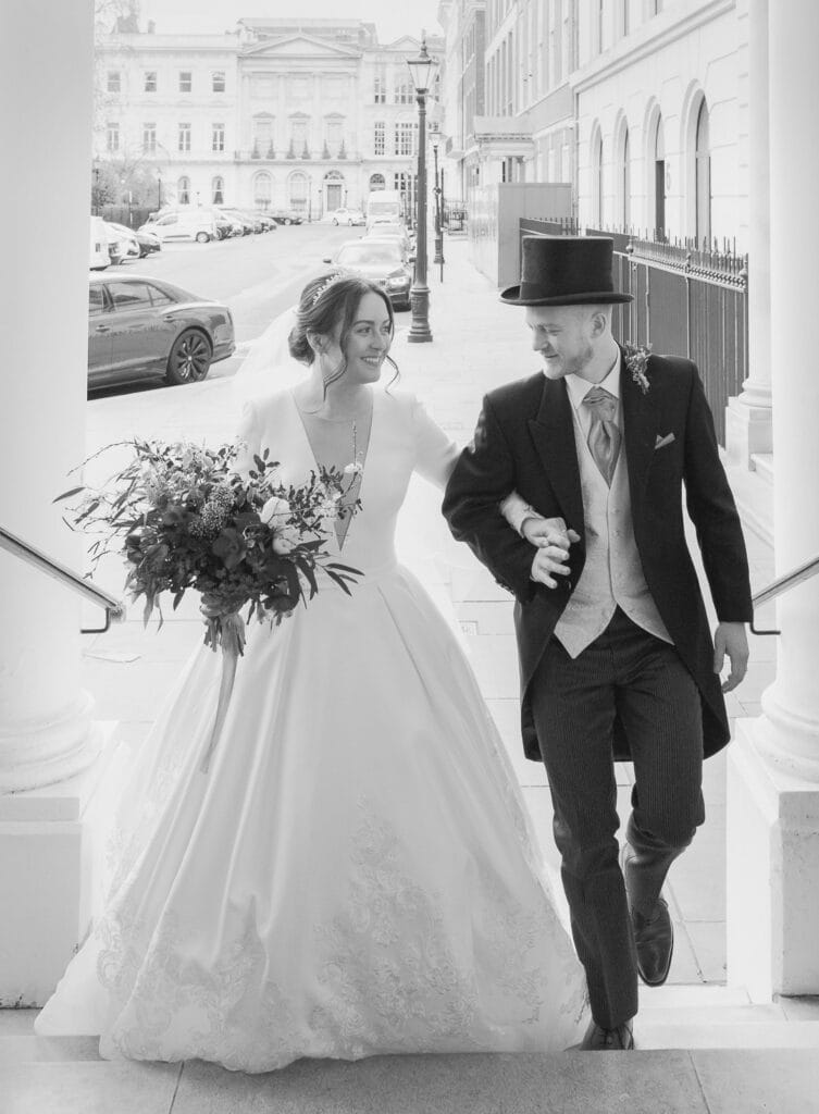 Bride and groom walk up the steps leading into the Naval and Military Club