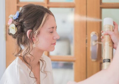 Stylist sprays bride's hair