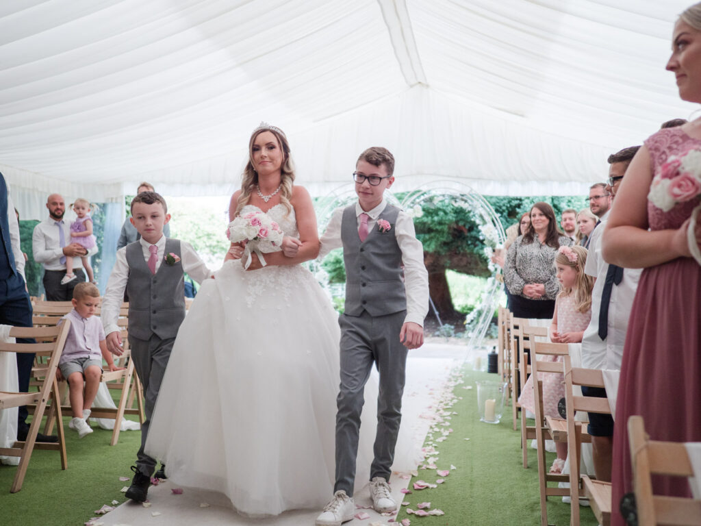 Bride escorted up the aisle by teenage boys