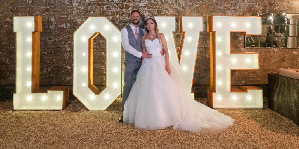 Bride and groom in front of illuminated LOVE sign
