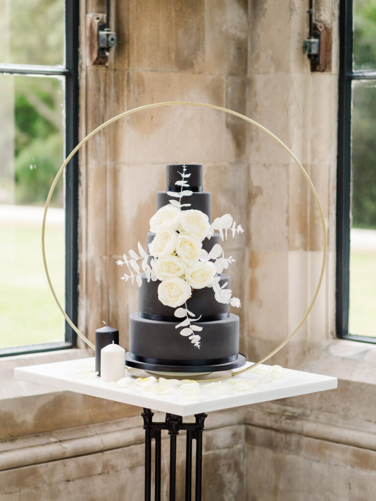 Black-iced five-tier wedding cake decorated with white roses