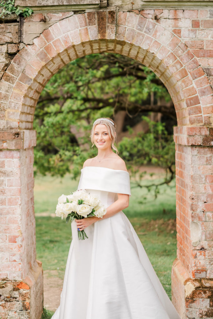 Bride beneath brick arch in garden