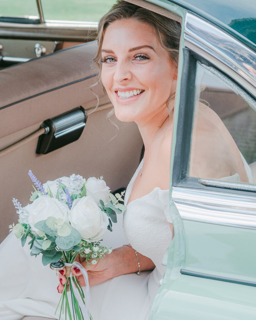 Bride smiles as she emerges from her wedding car