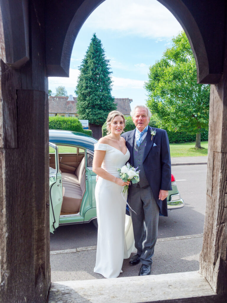 Bride and her father framed by a wooden arch