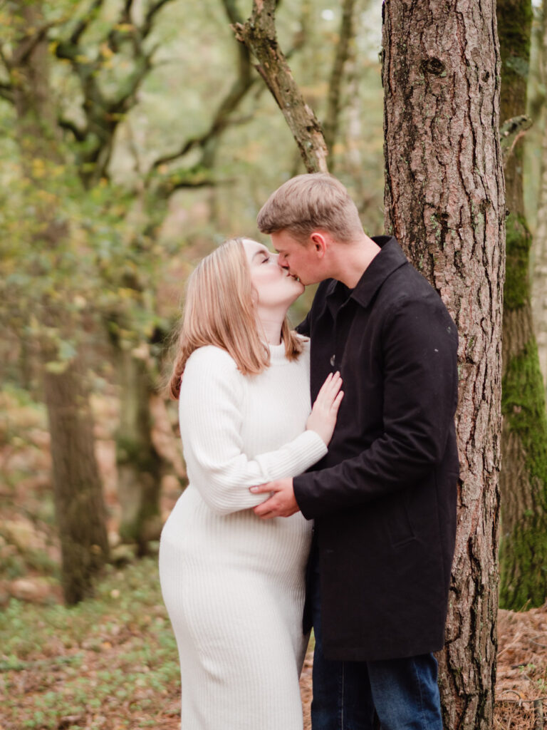 Smiling couple kiss in woodland