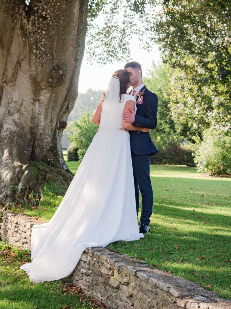 Bride and groom kiss in the garden at Clock Barn