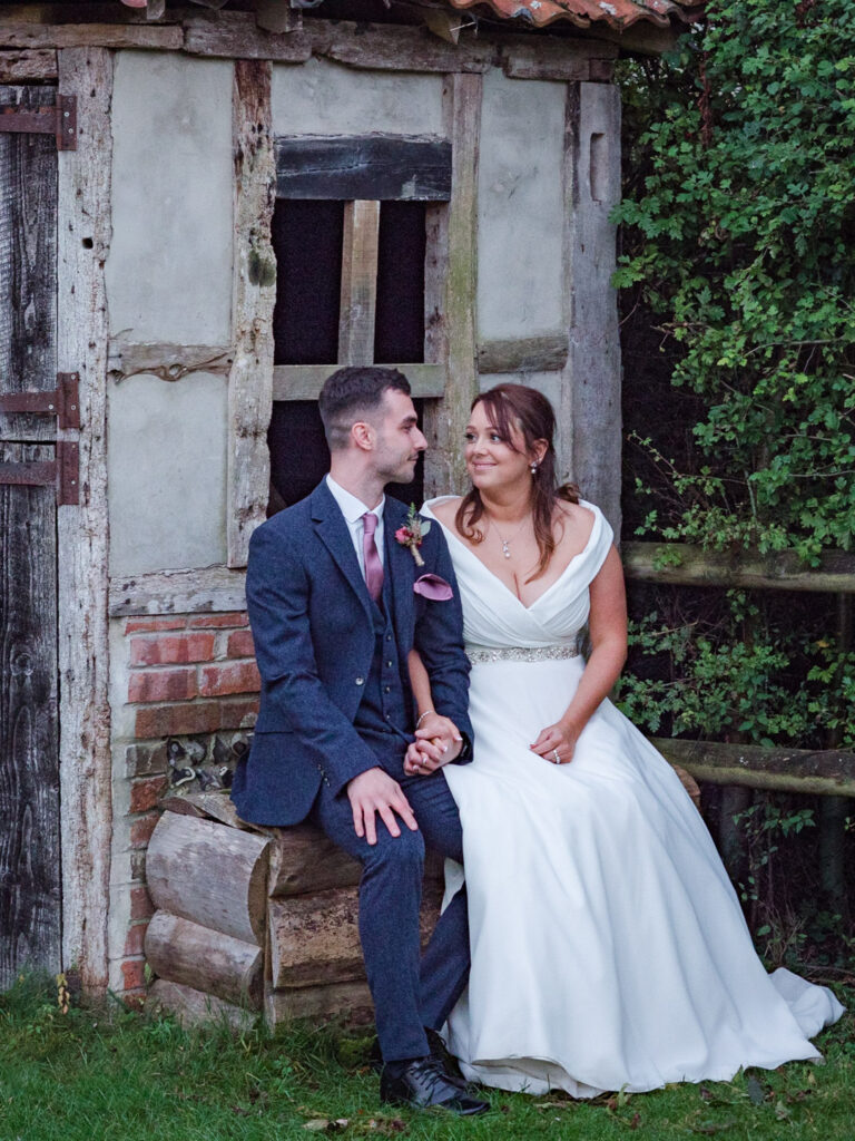 Bride and groom seated in the garden at Clock Barn