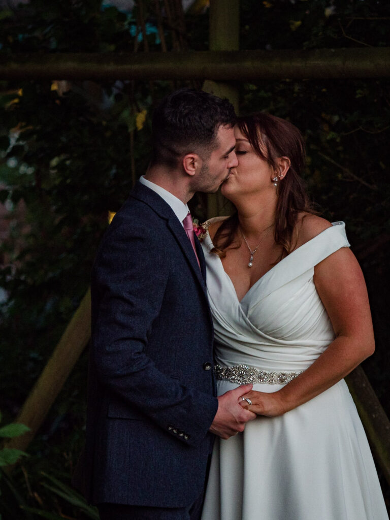 Bride and groom kiss in the garden at Clock Barn