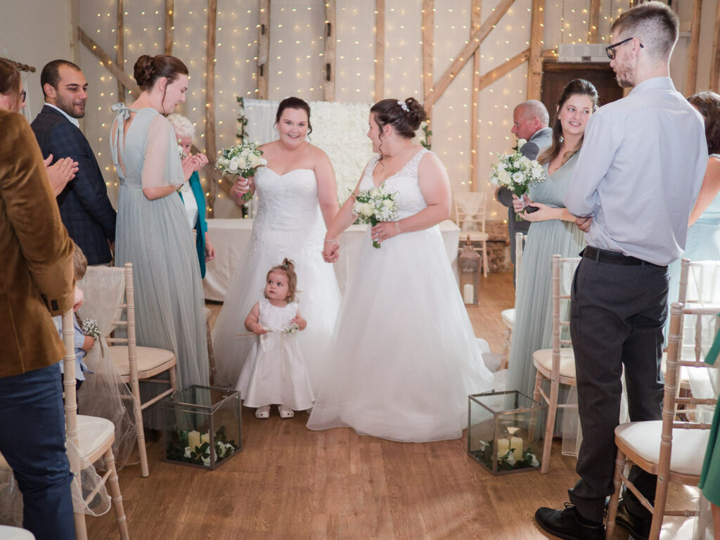 Newly-married brides walk down the aisle with their daughter