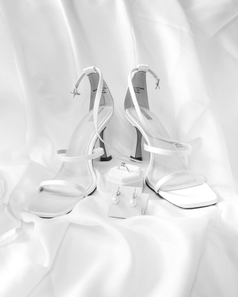 Shoes, earrings and engagement ring on white satin
