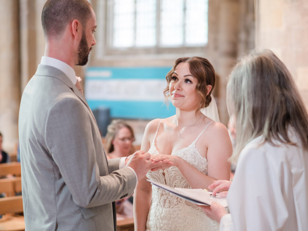 Groom places ring on bride's finger in Romsey Abbey