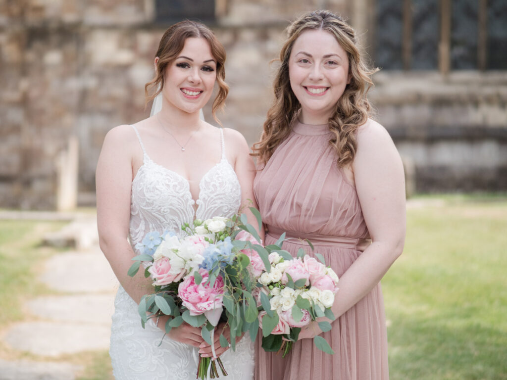Portrait of bride and her bridesmaid outside Romsey Abbey
