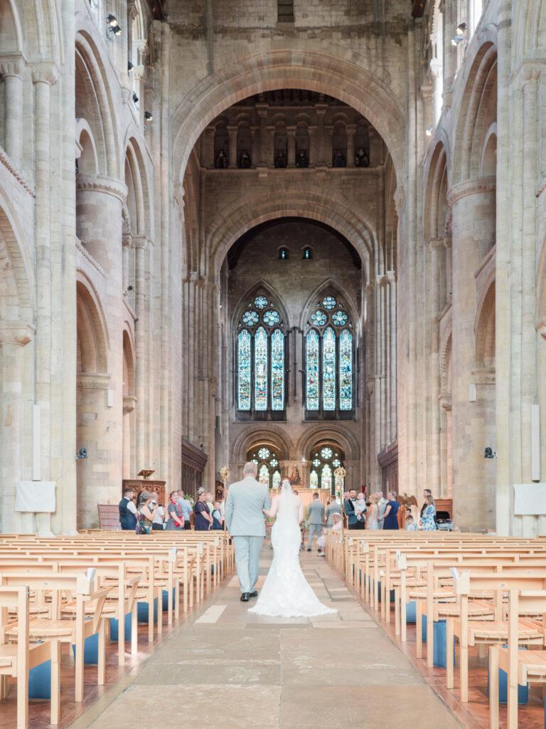 Bride and her father walk up the aisle in Romsey Abbey
