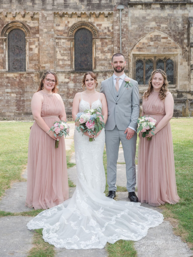 Bride, groom and bridesmaids outside Romsey Abbey