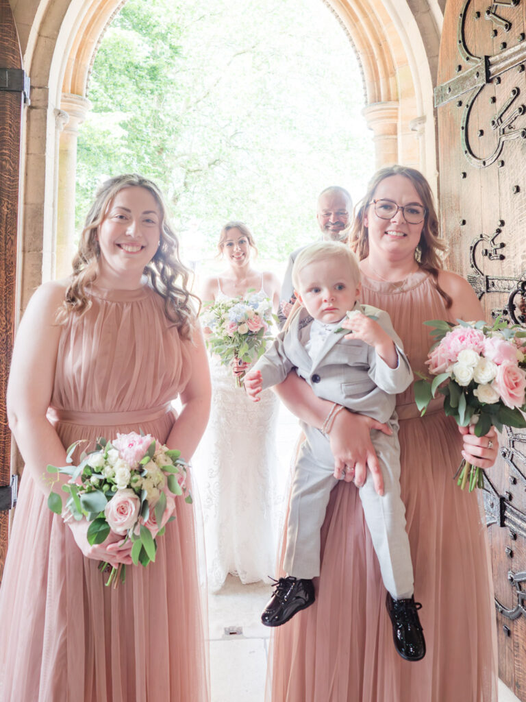 Bridesmaids smile in the doorway at Romsey Abbey