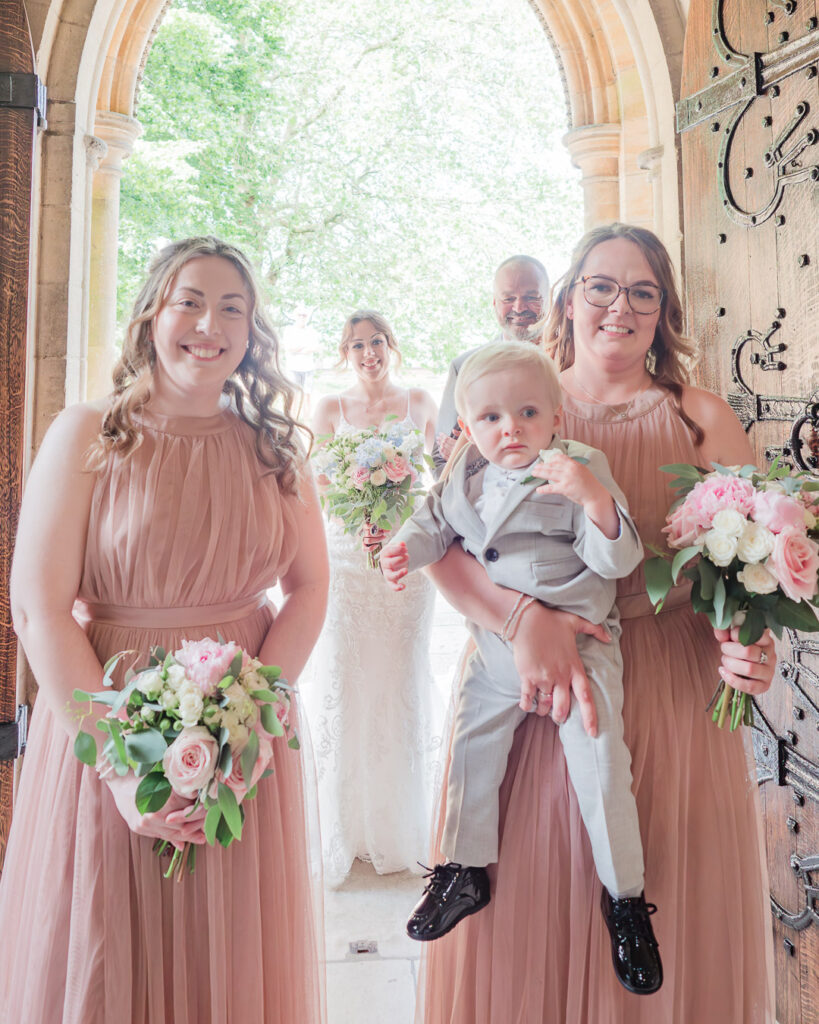 Bridesmaids smile in the doorway at Romsey Abbey