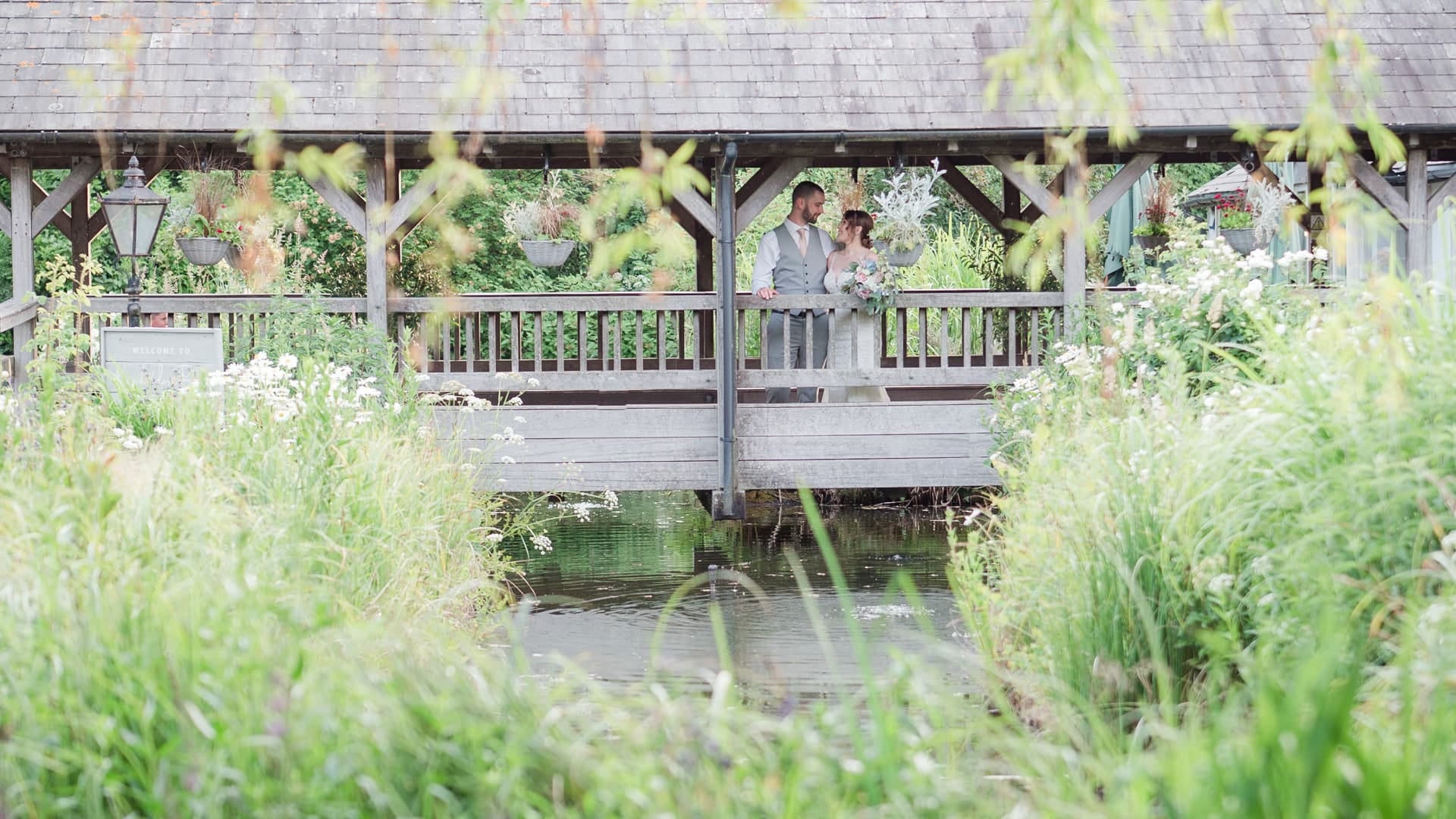 Groom holds his bride on a gravel path decorated with ornamental bay trees at The Orangery Suite