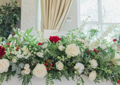 Close-up of top table décor at Carey's Manor – red and white roses with green foliage