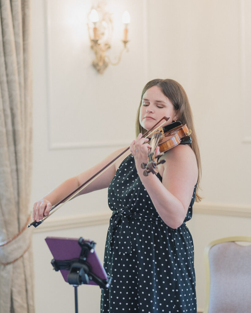 Hollie Chapman plays violin for wedding wearing a black and white polka dot dress