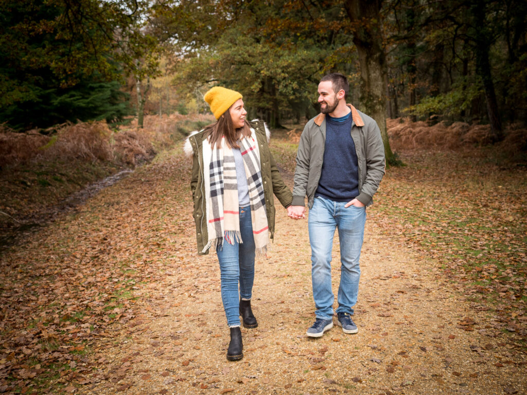 Couple walking hand-in-hand along a woodland track in autumn