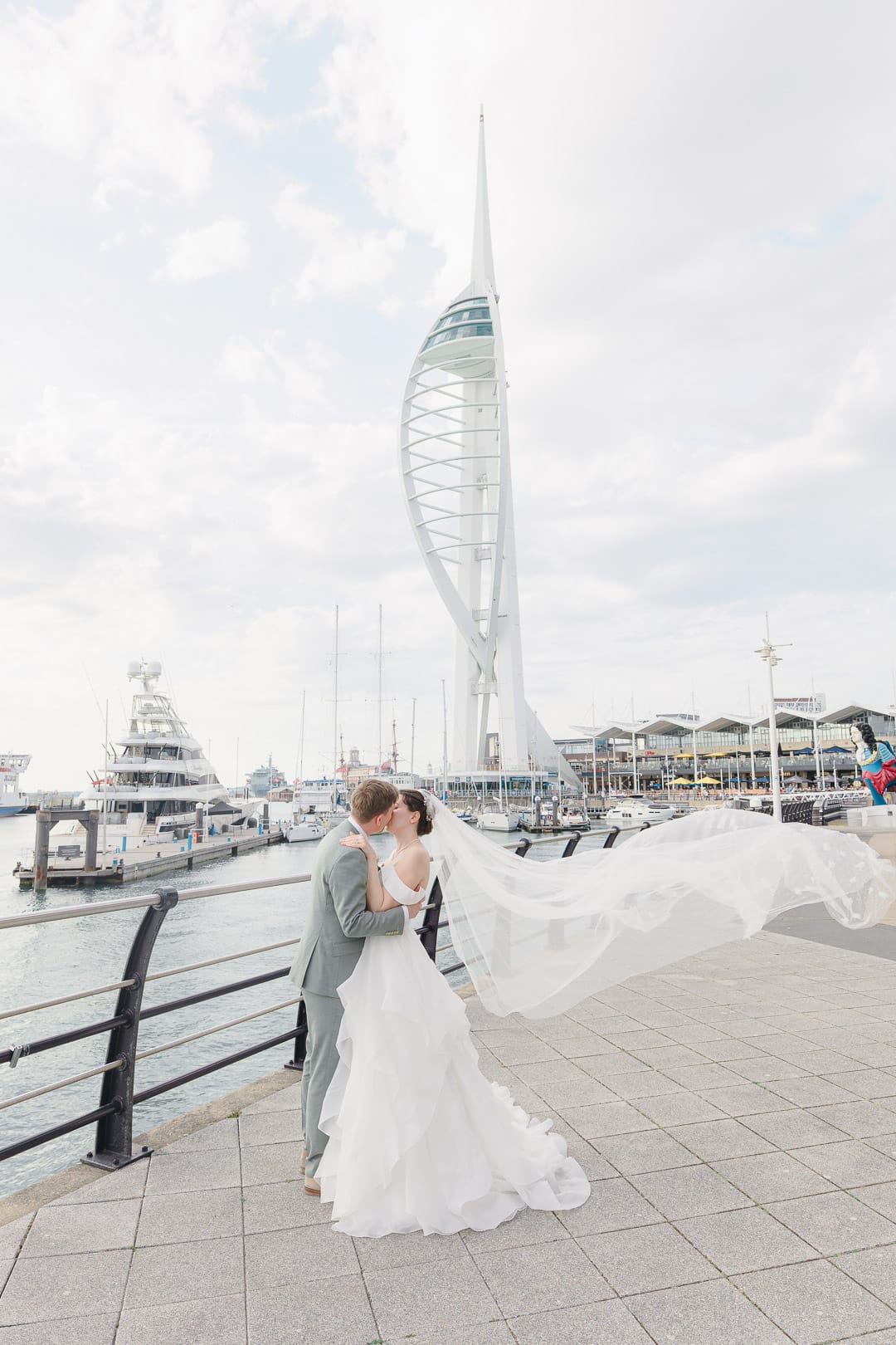 Spinnaker Tower wedding – bride's veil billows behind her as she kisses groom
