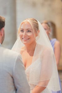 Bride smiles at groom as they exchange marriage vows during their Romsey Abbey wedding